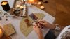 Personne réalisant un tirage de tarot dans une ambiance éclairée aux bougies