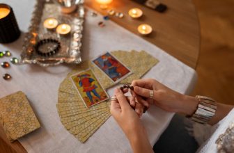 Personne réalisant un tirage de tarot dans une ambiance éclairée aux bougies